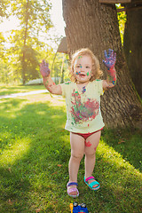 Image showing Two-year old girl stained in colors against green lawn