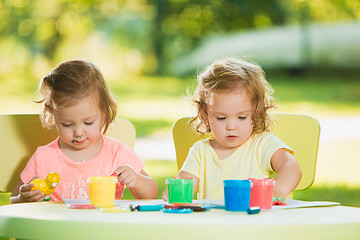 Image showing Two-year old girls painting with poster paintings together against green lawn