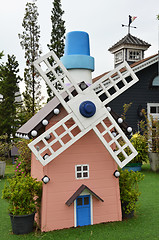 Image showing Small wooden mill standing on the green grass 