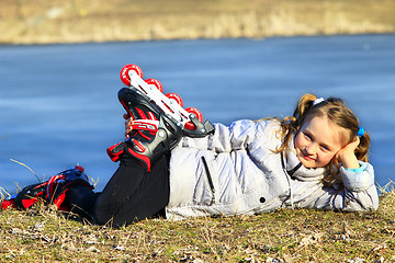 Image showing young girl in roller skates lays on the ground