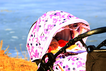 Image showing little baby sleeps in perambulator near the river