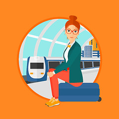 Image showing Woman sitting on suitcase at the train station.