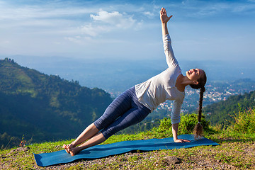 Image showing Woman doing yoga asana Vasisthasana - side plank pose outdoors