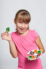 Image showing Happy little girl holding a plate with colorful jelly candies