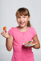 Image showing Happy little girl holding a plate with colorful jelly candies