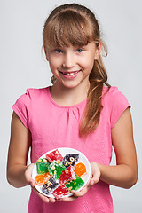 Image showing Happy little girl holding a plate with colorful jelly candies