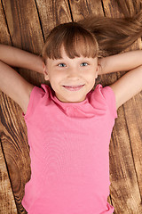 Image showing Top view of a smiling little girl lying on back