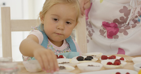 Image showing Child and woman preparing muffins on table