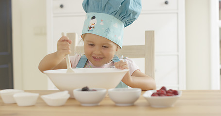 Image showing Adorable smiling toddler at mixing bowl