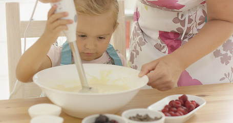 Image showing Serious pretty little girl concentrating on baking