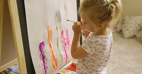 Image showing Little girl standing painting at an easel