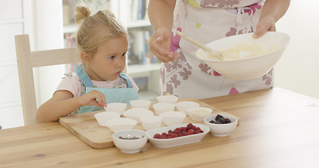 Image showing Little girl assisting Mum with the baking