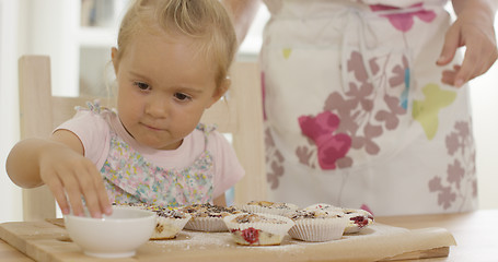 Image showing Close up on girl helping to prepare muffins