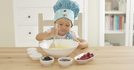 Image showing Adorable smiling toddler at mixing bowl