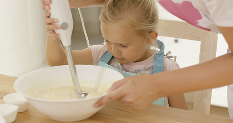 Image showing Cute little girl learning to bake from mother