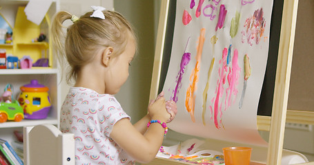 Image showing Creative little girl painting an abstract picture