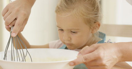 Image showing Fascinated little girl learning to bake