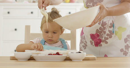 Image showing Pouring muffin batter into holders