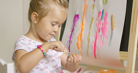 Image showing Little girl applying paint to the back of her hand