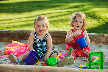 Image showing The two little baby girls playing toys in sand