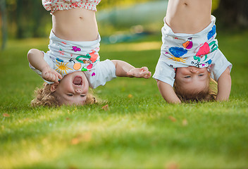 Image showing The two little baby girls hanging upside down