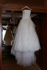 Image showing White Wedding dress hanging on a shoulders