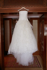 Image showing White Wedding dress hanging on a shoulders