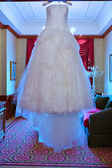 Image showing White Wedding dress hanging on a shoulders