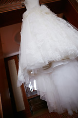 Image showing White Wedding dress hanging on a shoulders