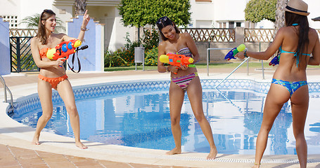 Image showing Three young women playing with colorful water guns