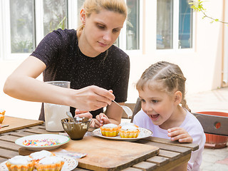 Image showing Mom puts confectionery glaze spoon on Easter cupcake, daughter happily looking