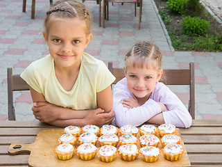 Image showing Two sisters sitting at a table on which are freshly baked Easter cupcakes