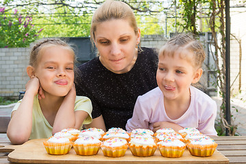 Image showing Mother and two daughters salivate looking at freshly Easter cupcakes