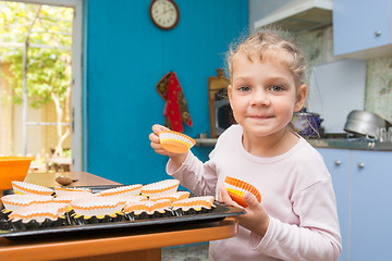 Image showing Five-year girl lays on a baking tins Easter cupcakes