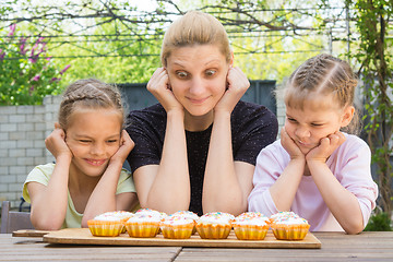 Image showing Mother and two daughters with different funny emotion looking at easter cupcakes