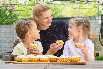 Image showing Mother and two daughters sitting at the table with Easter cupcakes in his hands