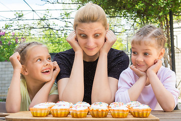 Image showing Mother and two daughters having fun and looking at easter cupcakes