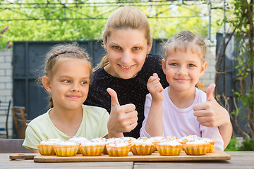 Image showing Mother and two daughters show a thumbs-up, and dress easter cupcakes