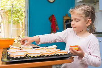 Image showing The child lays on a baking tins Easter cupcakes