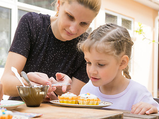 Image showing Mother pours a bag of confectionery posypku on Easter cupcake, daughter happily looking