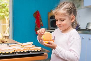 Image showing The child is prepared for the feast of Easter, laying on a baking tins Easter cupcakes