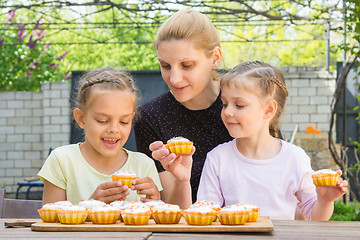 Image showing Mother and two daughters sitting at the table with Easter cupcakes and they are risen