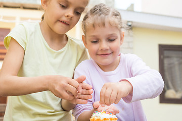 Image showing Two girls sprinkle confectionery on Easter cupcakes