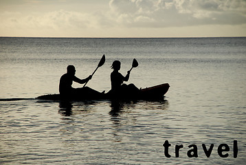 Image showing Kayakers silhouetted on the ocean, TRAVEL as concept text