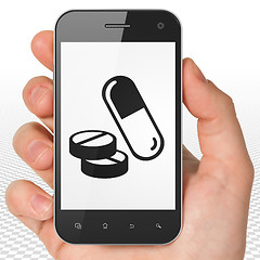 Image showing Medicine concept: Hand Holding Smartphone with Pills on display