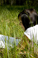Image showing pretty young girl reading on the grass