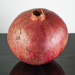 Image showing  half ripe pomegranate fruit isolated on black wooden plane and white background 