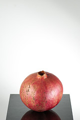 Image showing  half ripe pomegranate fruit isolated on black wooden plane and white background with copyspace