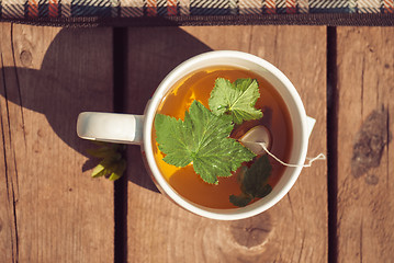 Image showing Top view of tea with currant leaf in white cup. Horizintal image