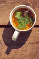 Image showing Top view of tea with currant leaf in white cup. Vertical image